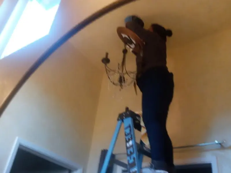 Electrician installing a chandelier in a Salisbury residence